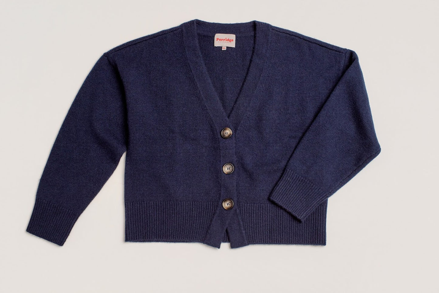 Navy blue cardigan with tortoiseshell buttons on a plain background