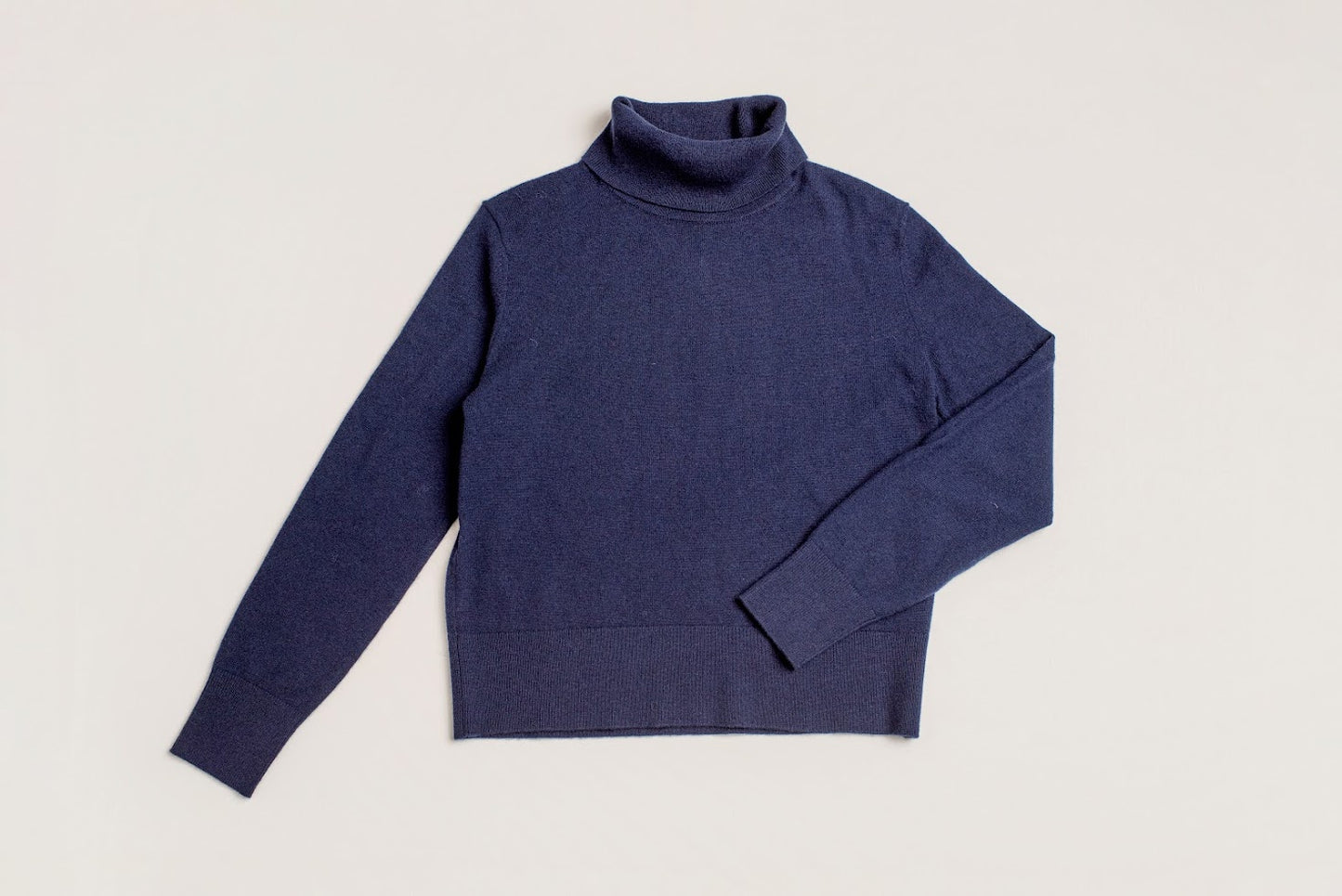Blue turtleneck sweater on a light gray background