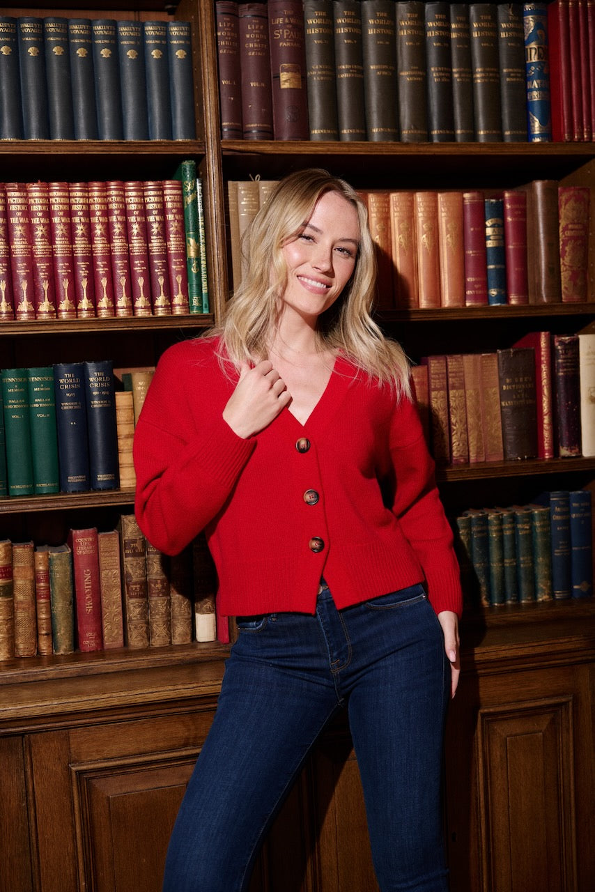 blonde lady in a red wool and cashmere cardigan with blue jeans