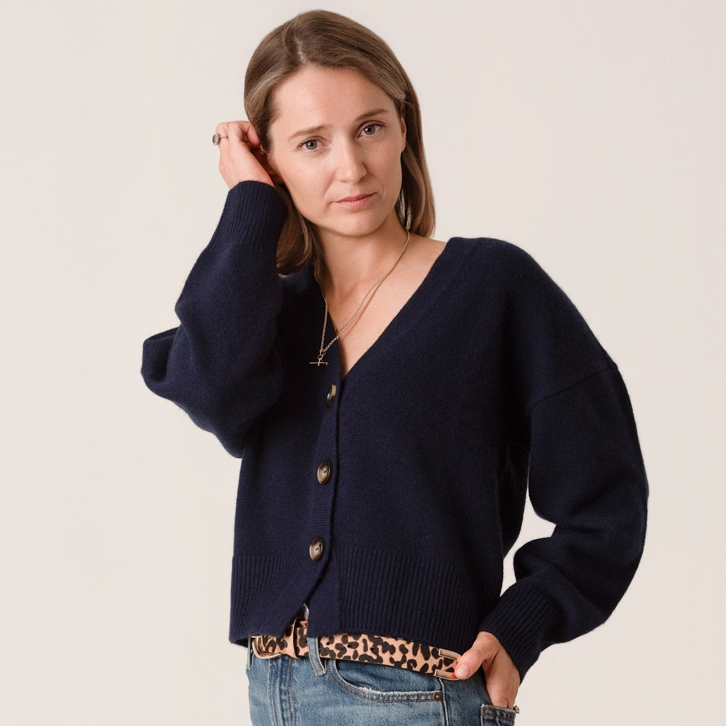 Woman wearing a navy blue wool and cashmere cardigan with a plain background