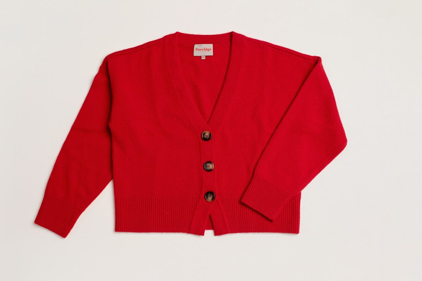 Red wool and cashmere cardigan with three buttons on a light background