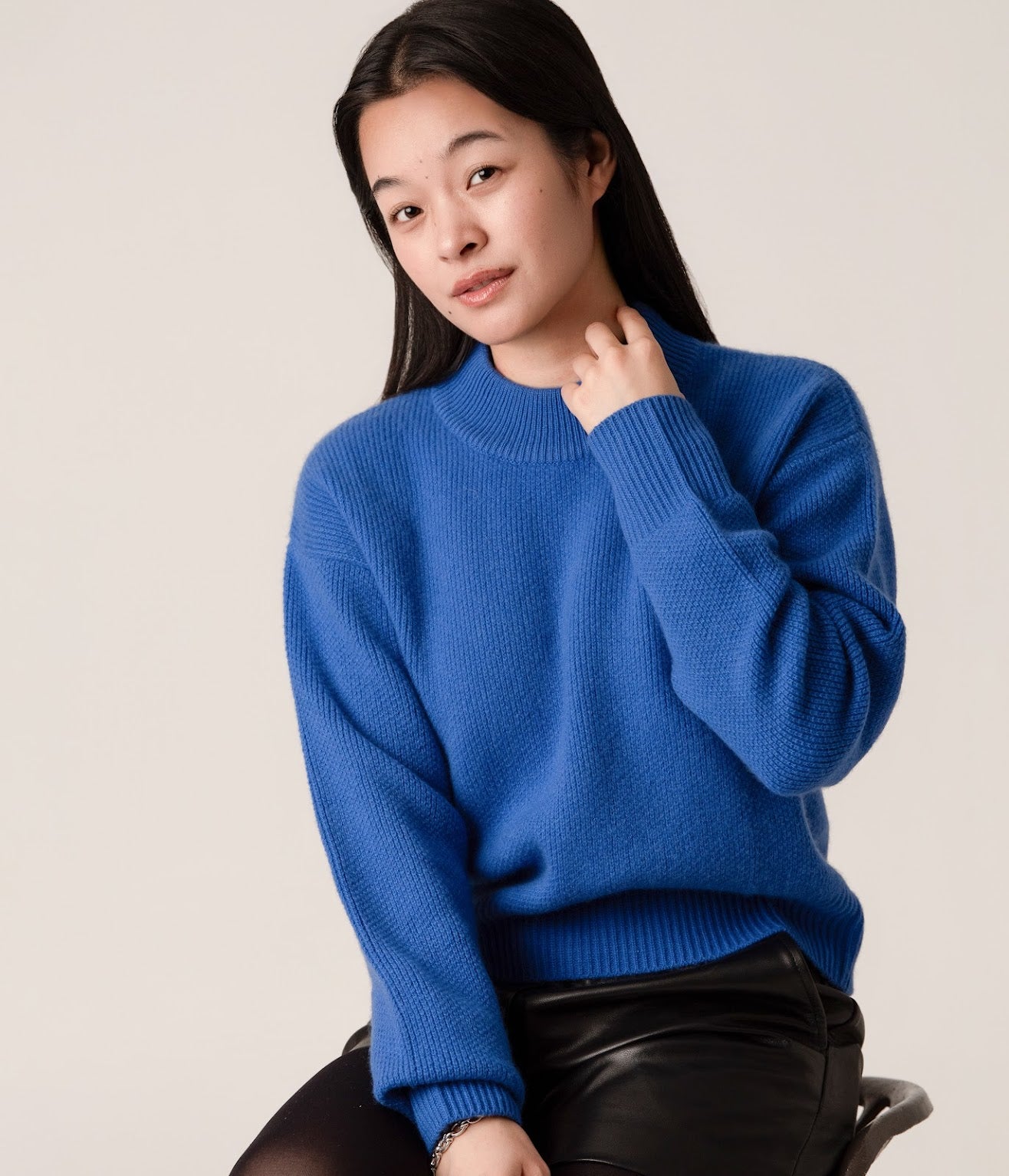 Person wearing a blue wool and cashmere sweater with black leather shorts